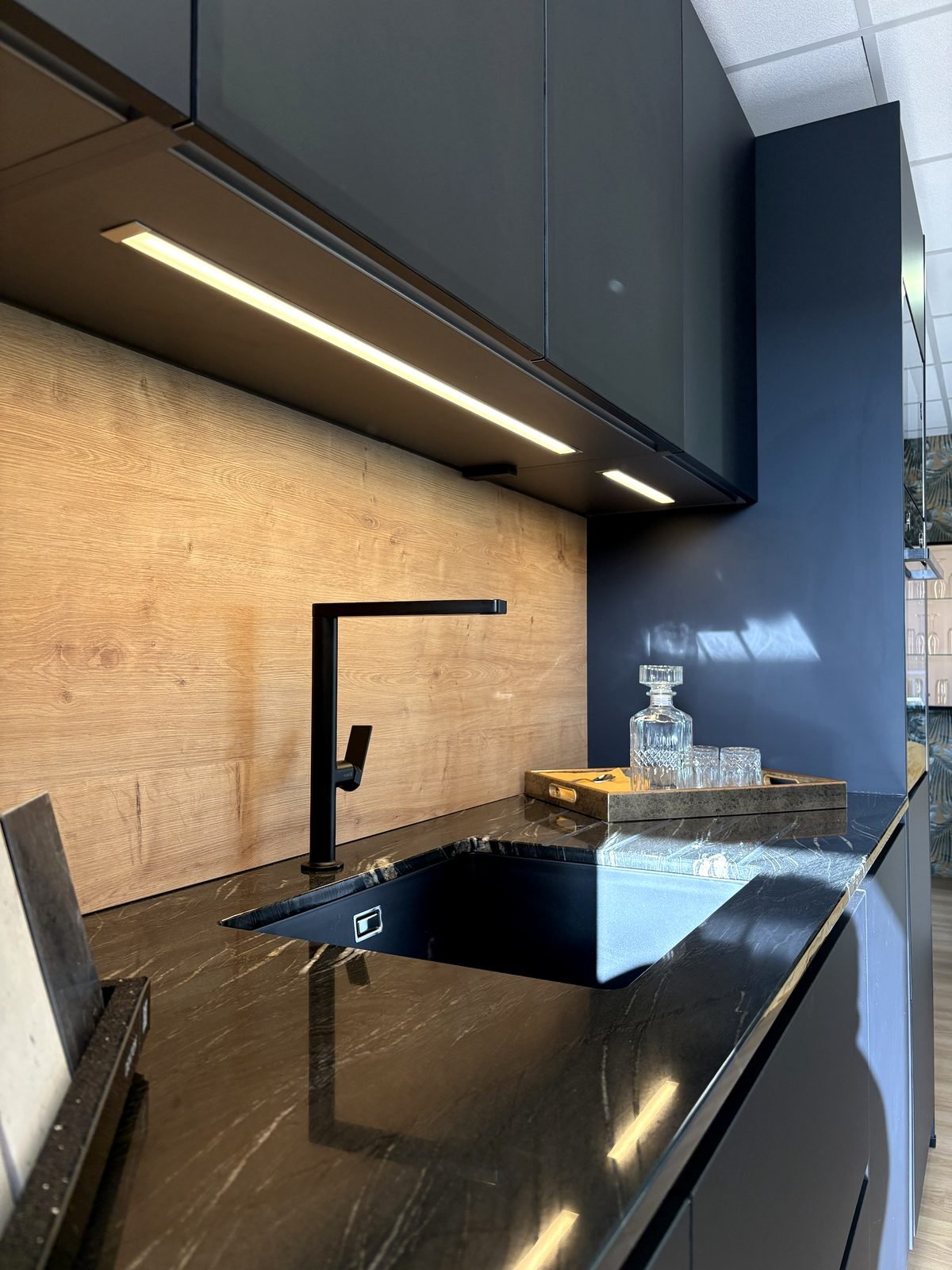 Évier granit noir et mitigeur noir sous un éclairage LED, au showroom